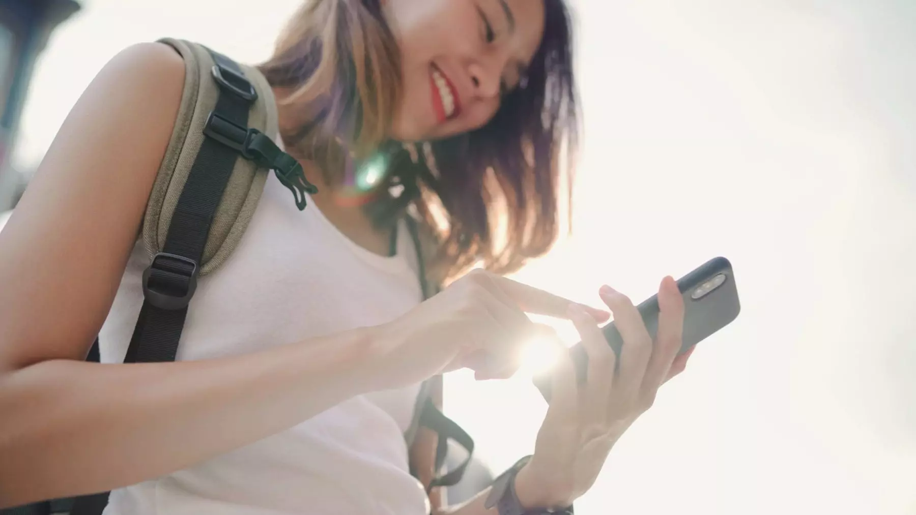 AnyConv.com cheerful asian backpacker blogger woman using smartphone direction looking location map